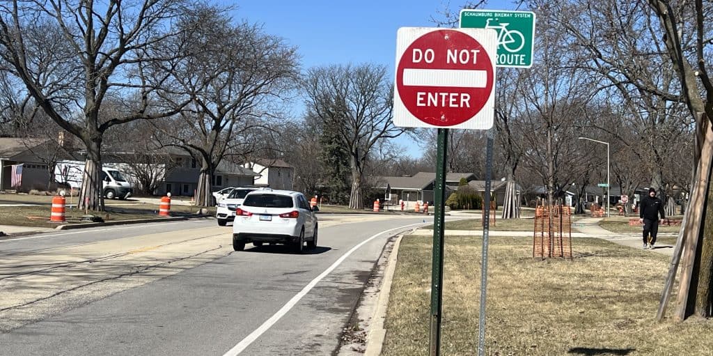 Looking down a residential street with bike lane, with a Do Not Enter sign partially covering a Bike Route sign up front.
