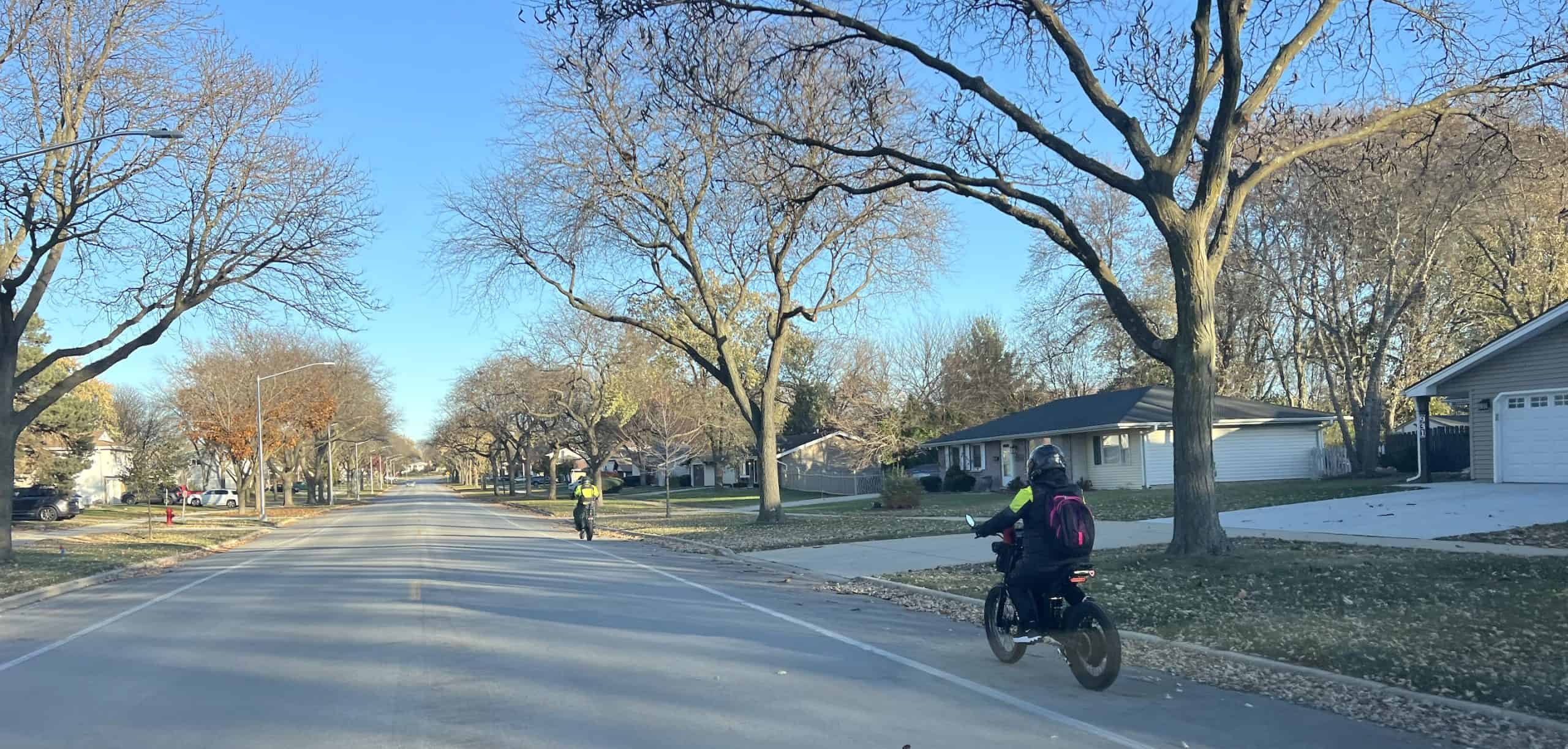 Bike riding in suburban Chicago neighborhood with leafless trees and clear blue sky.