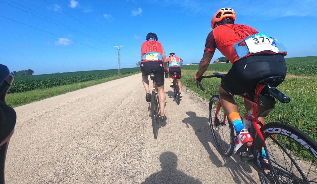 A cyclist group riding on a rural road in suburban Chicago, sunny day, outdoor biking activity.