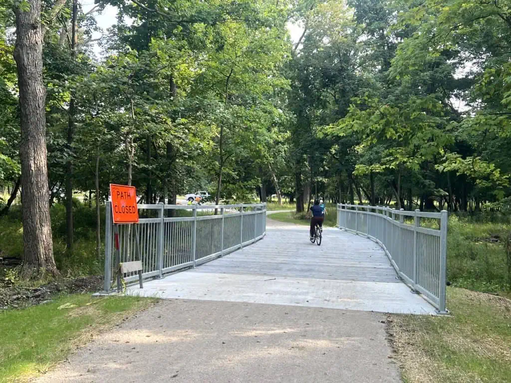 Pedestrian and cyclist on a bridge in a green park in suburban Chicago.