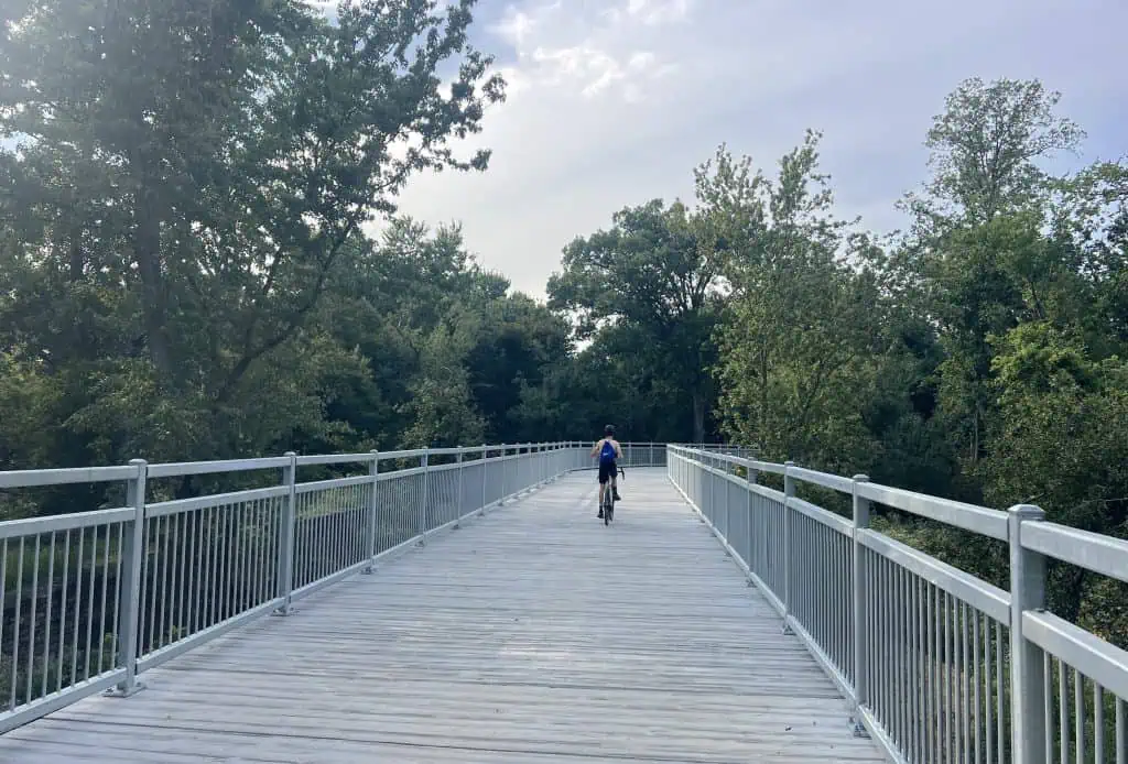 Cyclist riding on a wooden bridge surrounded by trees in suburban Chicago.